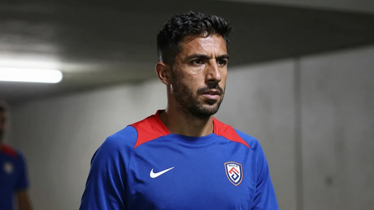 A close-up shot of a 35-year-old male coach, dressed in a plain blue and red Málaga CF training top, made of a...