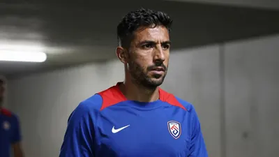 A close-up shot of a 35-year-old male coach, dressed in a plain blue and red Málaga CF training top, made of a...