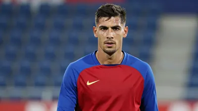 Mid-30s muscular Málaga CF midfielder, head-and-shoulders, intense gaze, sweat glistening on brow, wearing a plain blue...