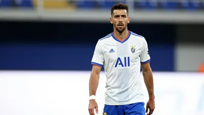 A photorealistic image of an anonymous Málaga CF center-back in his 30s, wearing a white jersey with blue stripes and a...