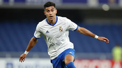 A 28-year-old Málaga CF midfielder in a tight action crop, wearing a white jersey with blue shorts and socks, with the...
