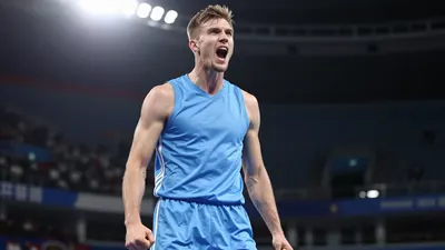 Athletic 20-25 year old forward in solid light blue kit, mid-celebration after scoring, blurred stadium background