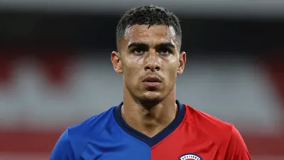 Mid-20s muscular midfielder, intense gaze, head-and-shoulders framed, wearing a plain, unmarked training top split blue...