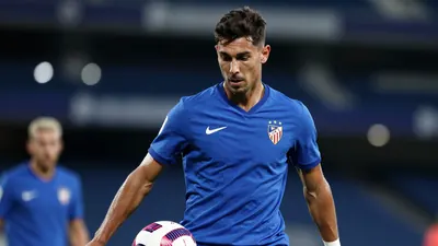 A mid-30s anonymous Málaga CF midfielder, waist-up, wearing a solid blue kit, focused on the ball, background blurred...