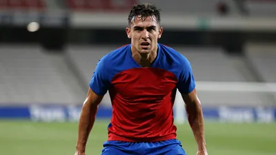 Mid-20s Málaga forward, muscular, intense expression, drenched in sweat, blue and red training shirt (solid halves...