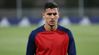 Mid-30s muscular Málaga CF midfielder, head-and-shoulders, eyes focused and slightly furrowed, wearing a plain blue and...