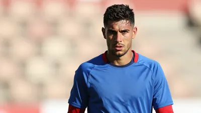 A rugged, 28-year-old Málaga CF midfielder, dressed in a plain blue and red training top, intense expression...