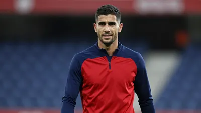Mid-30s muscular Málaga CF midfielder, waist-up, wearing a plain blue and red training top (solid navy sleeves, crimson...