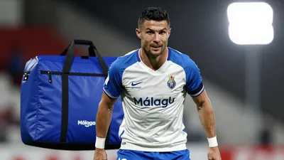 A photorealistic image of an anonymous Málaga CF player in his mid-20s, with a strong build, wearing a white jersey with...