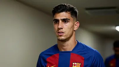A close-up shot of a 28-year-old, ruggedly-built Málaga CF left-back, wearing a plain blue and red striped training top...