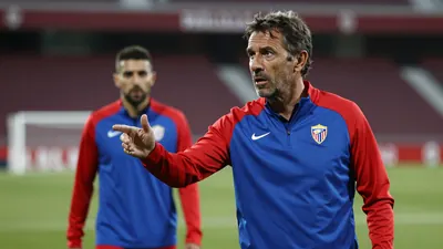 A 35-year-old, ruggedly-built, middle-aged assistant coach of Málaga CF, dressed in a plain, unmarked blue and red...