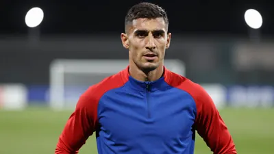 Mid-30s muscular midfielder, waist-up, face bright and focused, short dark hair, slight stubble, wearing a plain blue and...